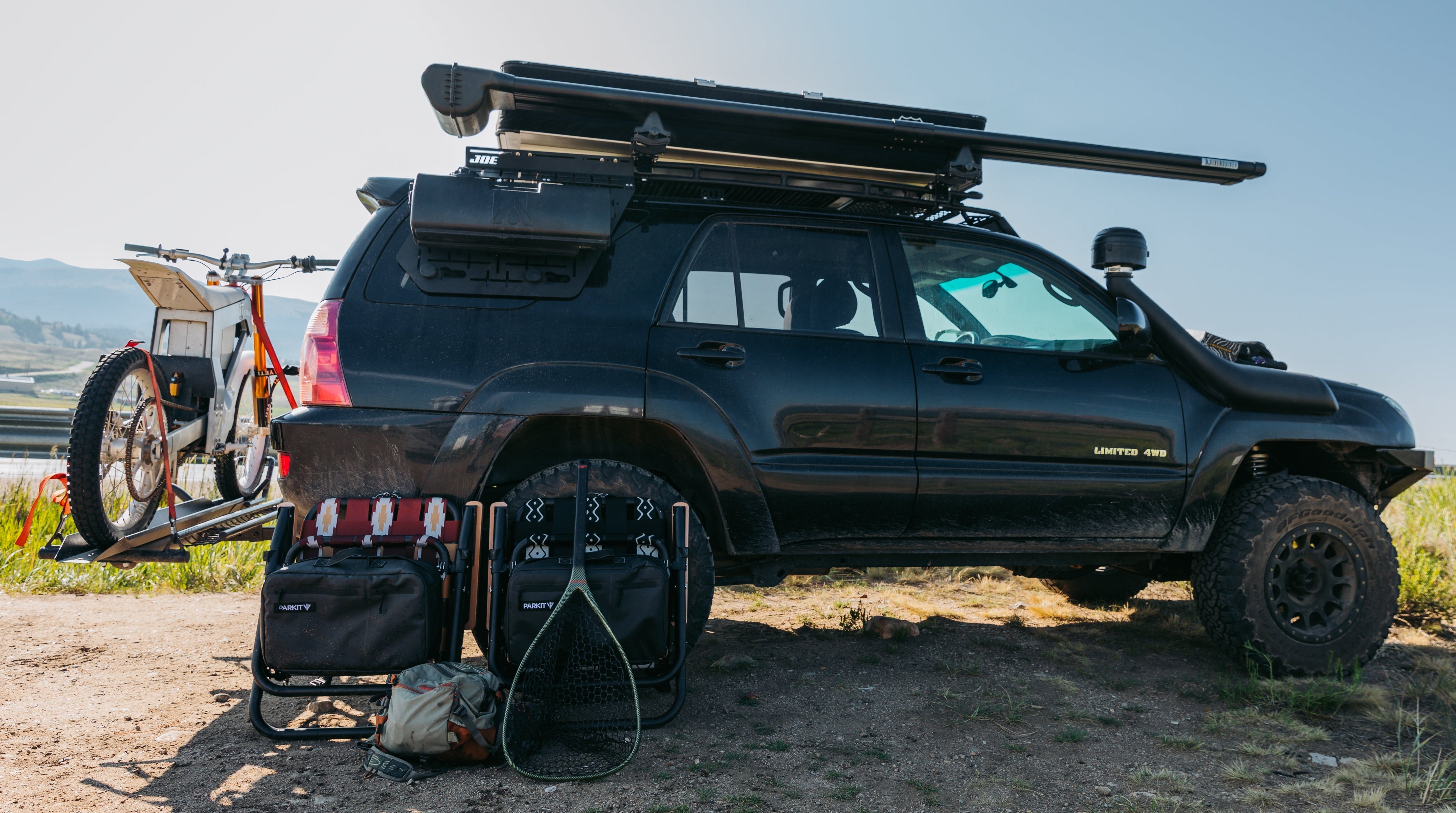 Voyager folding hunting chair set up in next to an overland vehicle