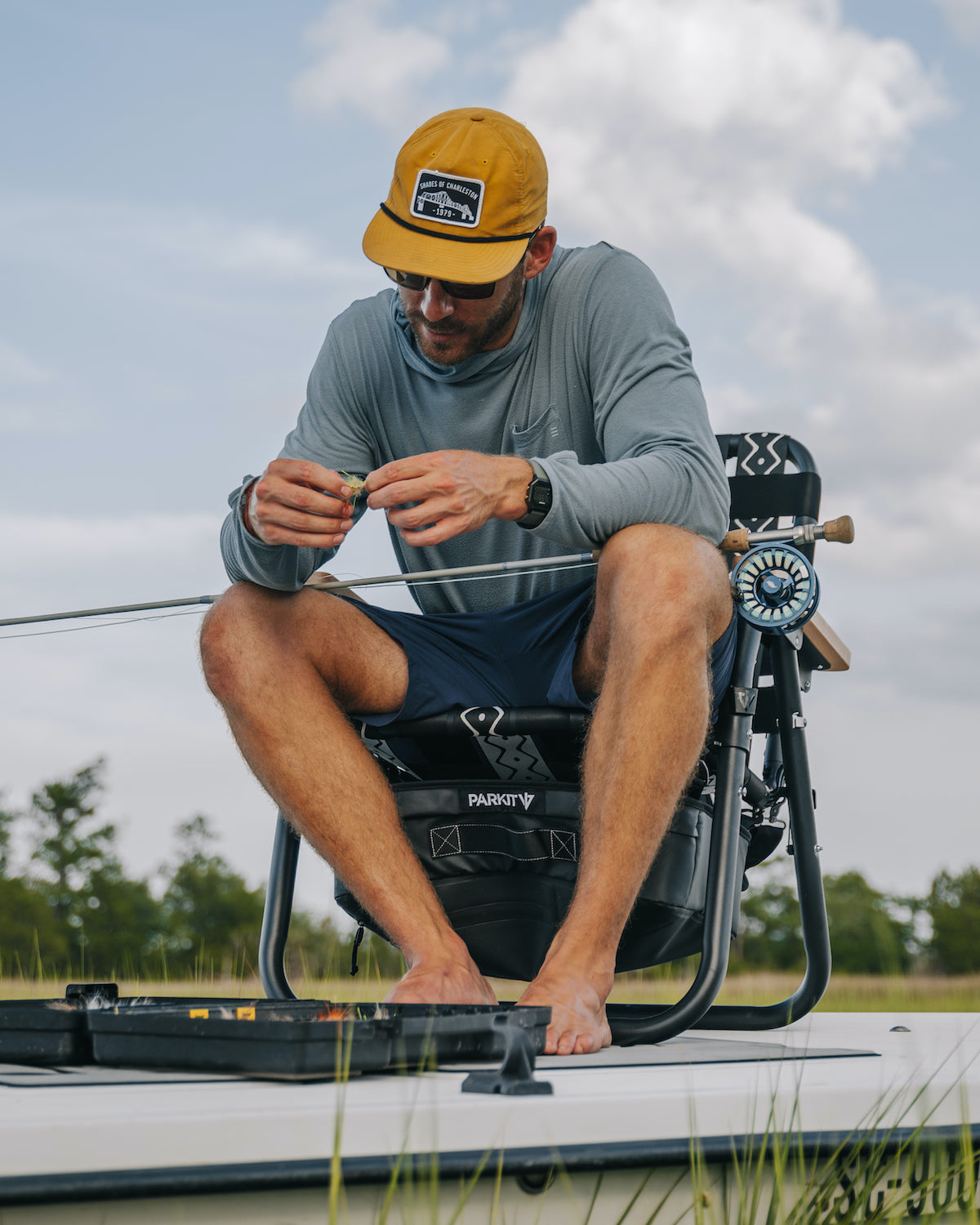 A Man sitting in his Voyager outdoor chair on a boat as he prepares to go fishing.