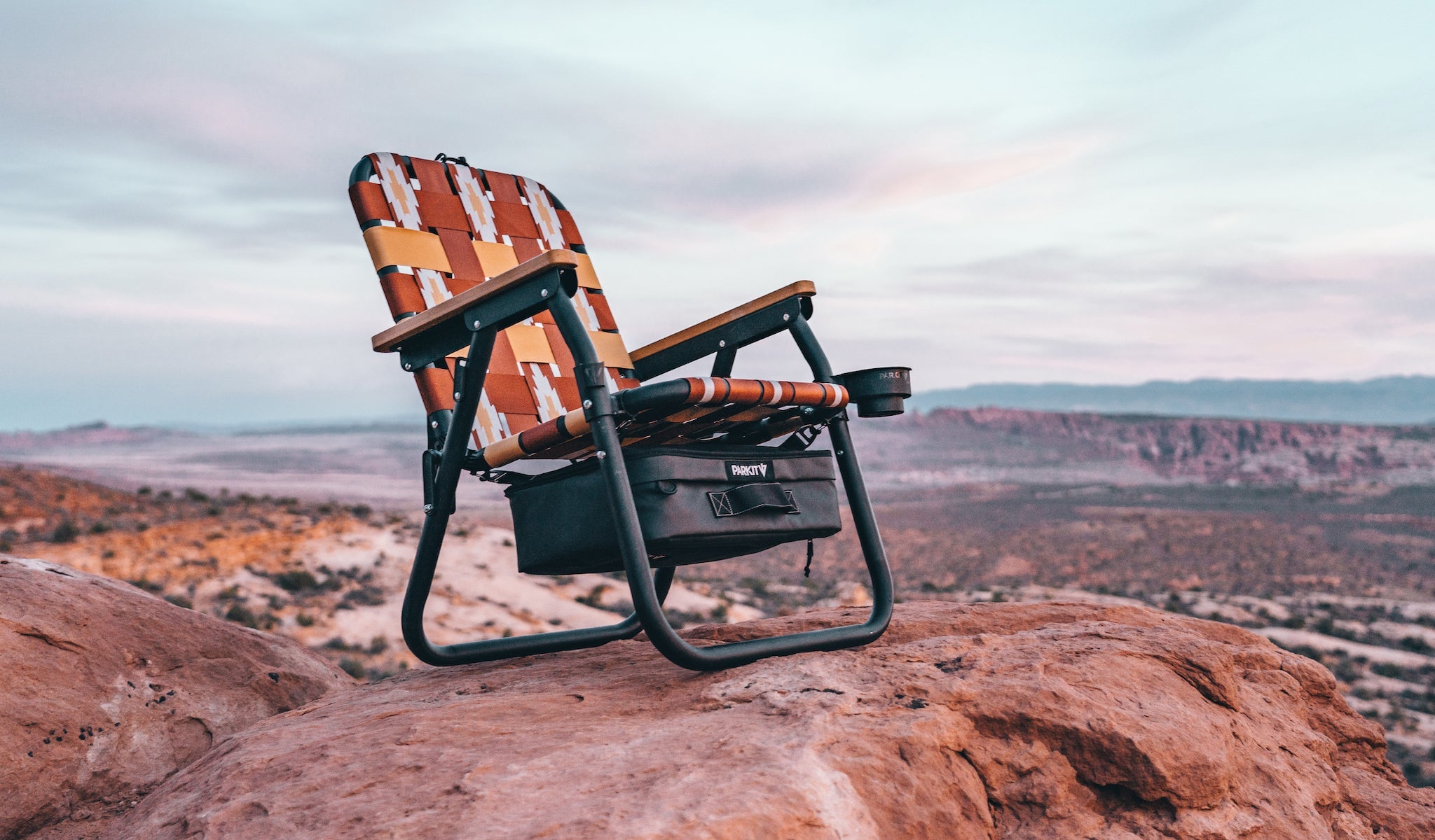 Voyager camping Chair in Calico by PARKIT on red rock in Arches National Park as the sun rises.
